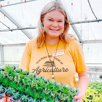 Female proudly holding container of succulent plants 