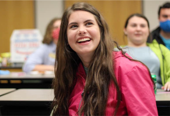 young brunette female student wearing a red jacket, smiling 