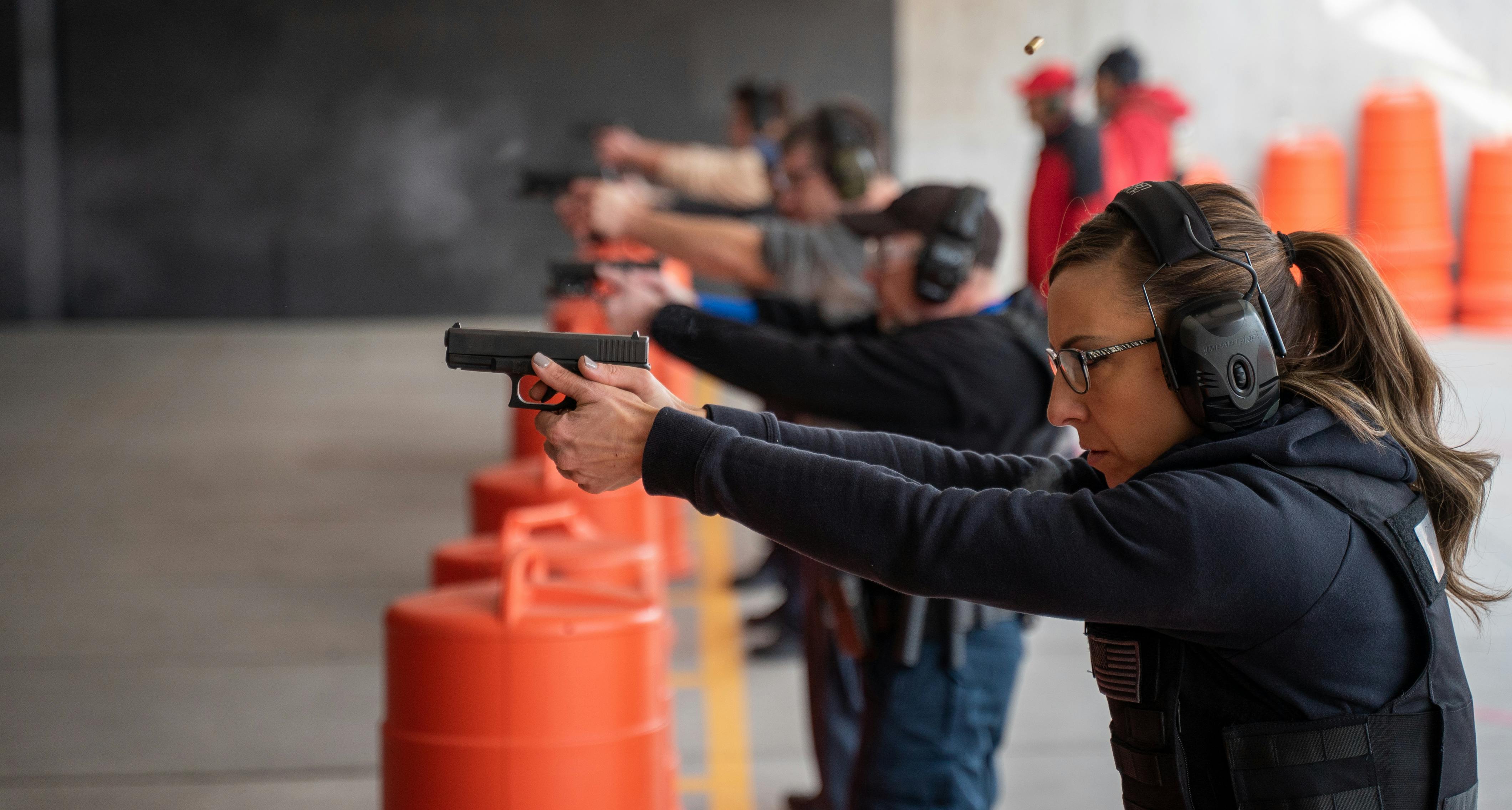 a row of students standing behind orange barrels shooting guns