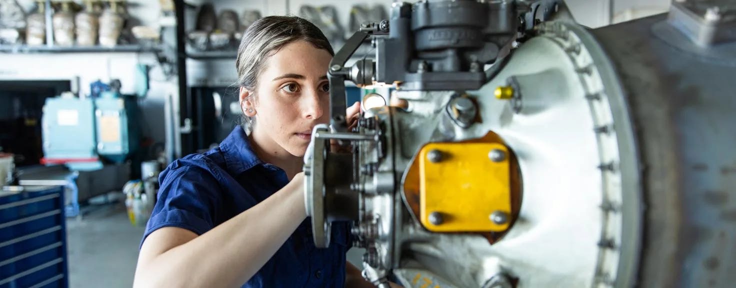 A woman works on an aircraft engine