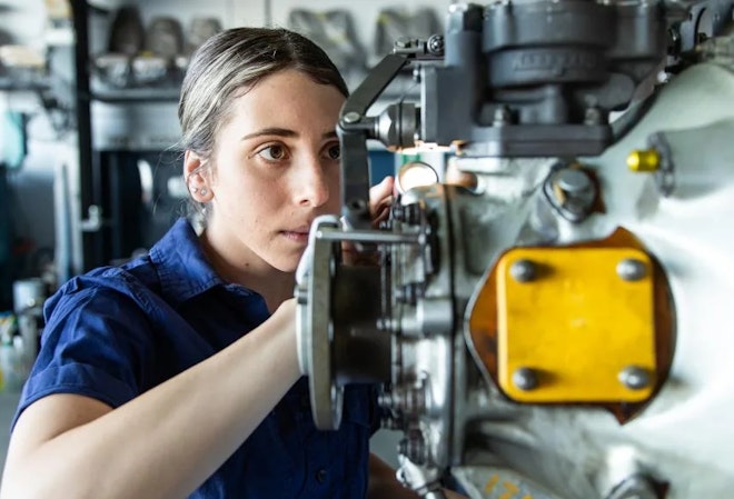 A woman works on an aircraft engine