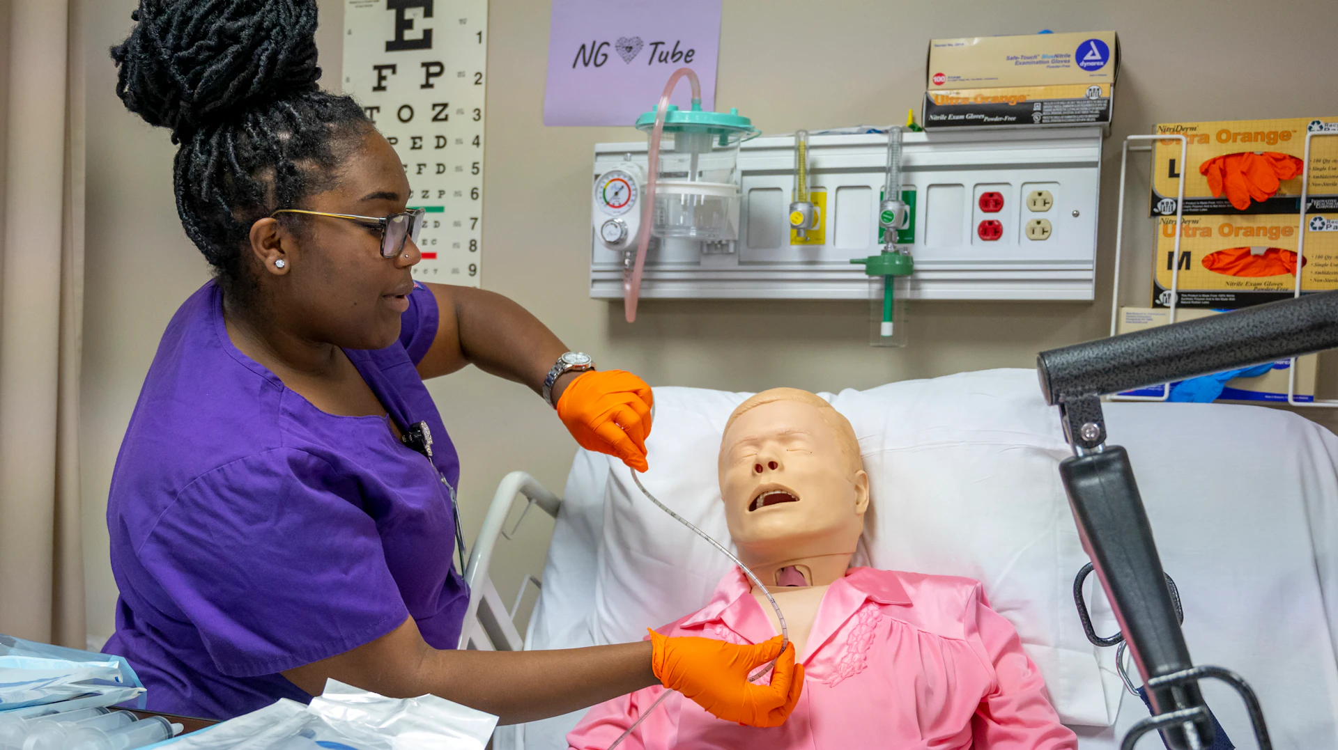 A nursing student practices NG tube insertion on a patient simulator in a clinical skills lab.