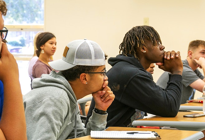 Students listening intently to their professor while siting at their desk