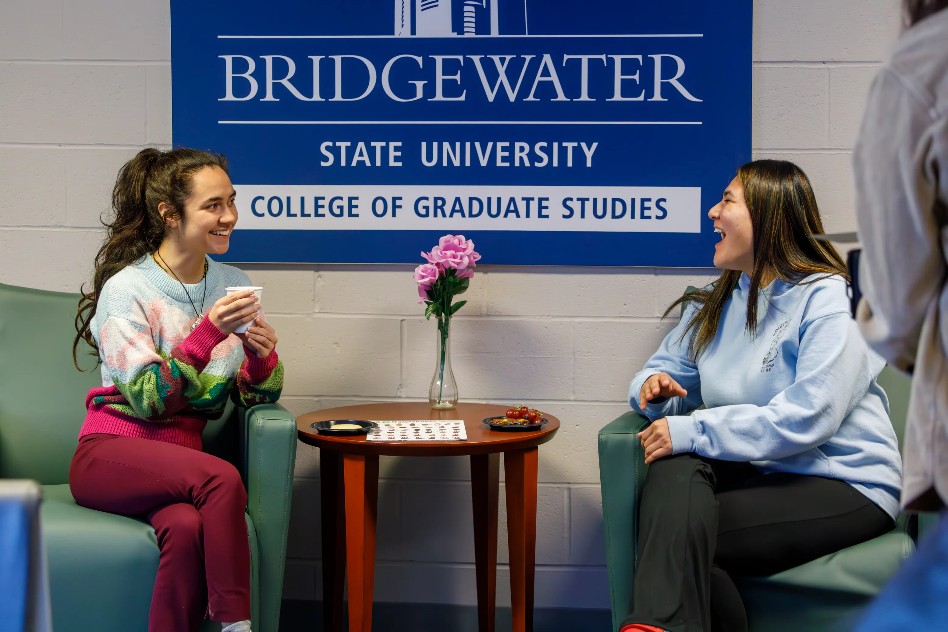 Two students laughing in a Bridgewater State University graduate-studies lounge