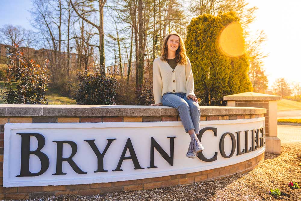 Student sitting on Bryan College Sign