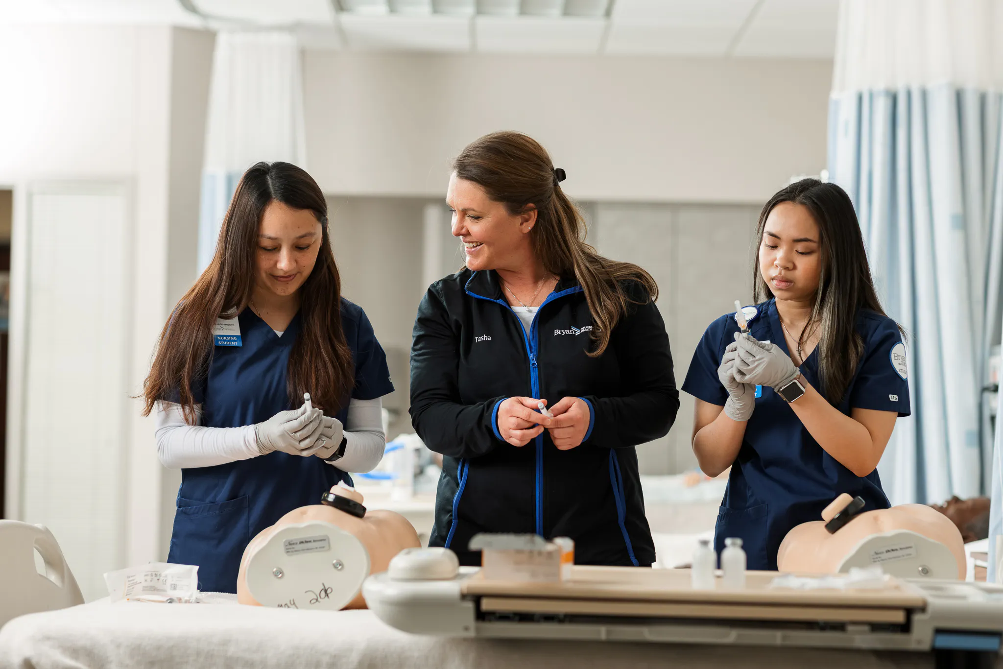 Nursing faculty teaching students how to use needle while drawing blood.