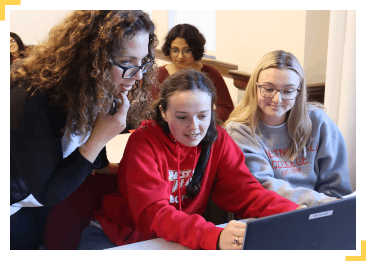 Students and teacher looking at laptop