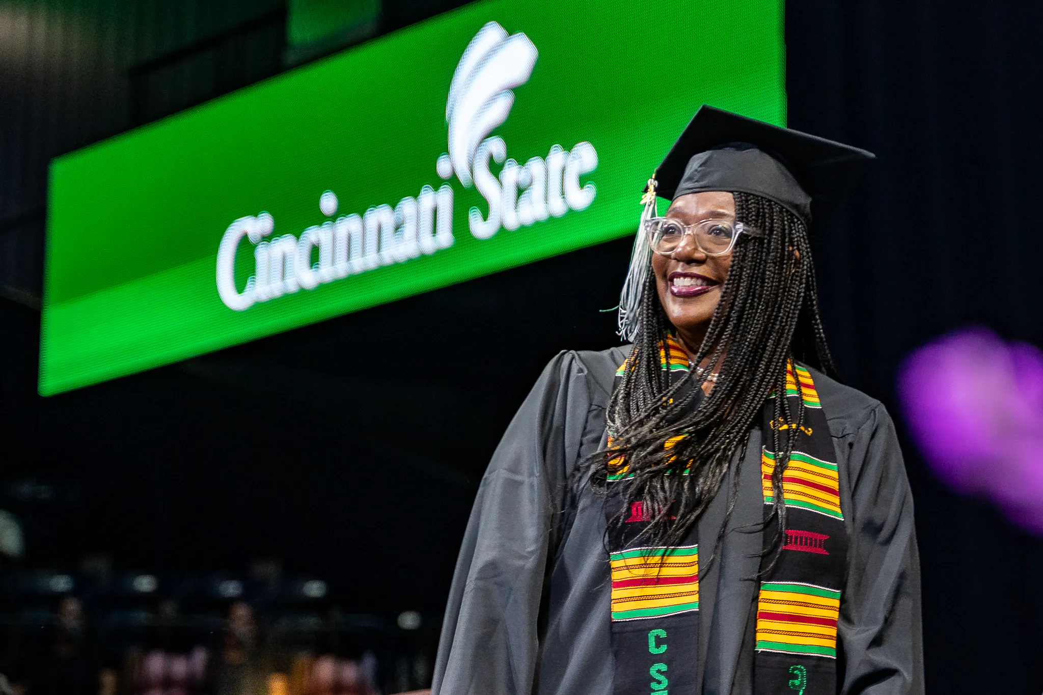 student on stage at commencement with Cincinnati State sign in the background