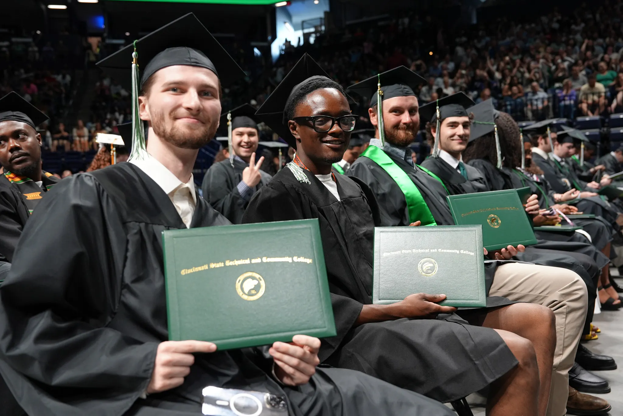 students at commencement holding diplomas