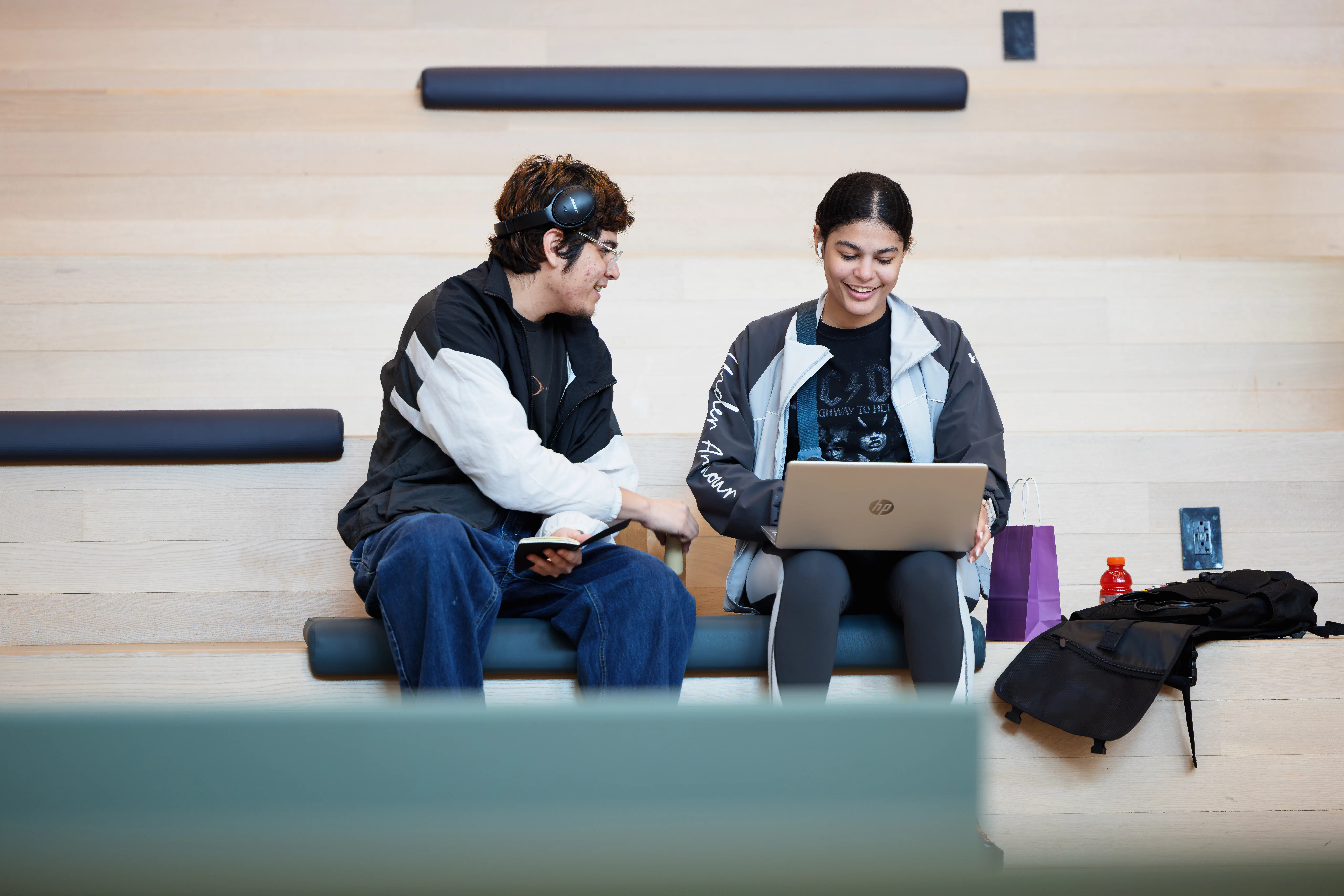 Two students sitting on steps and looking at laptop.