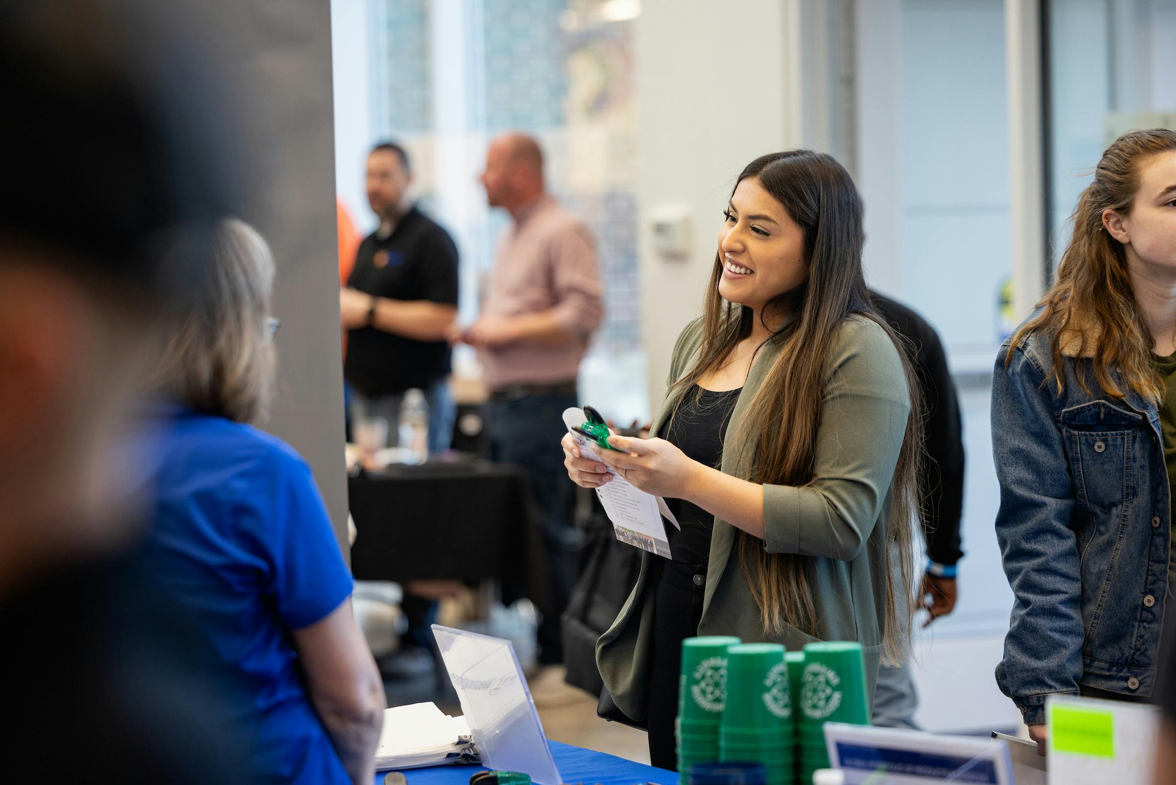 Student holding swag items, speaking with an employer