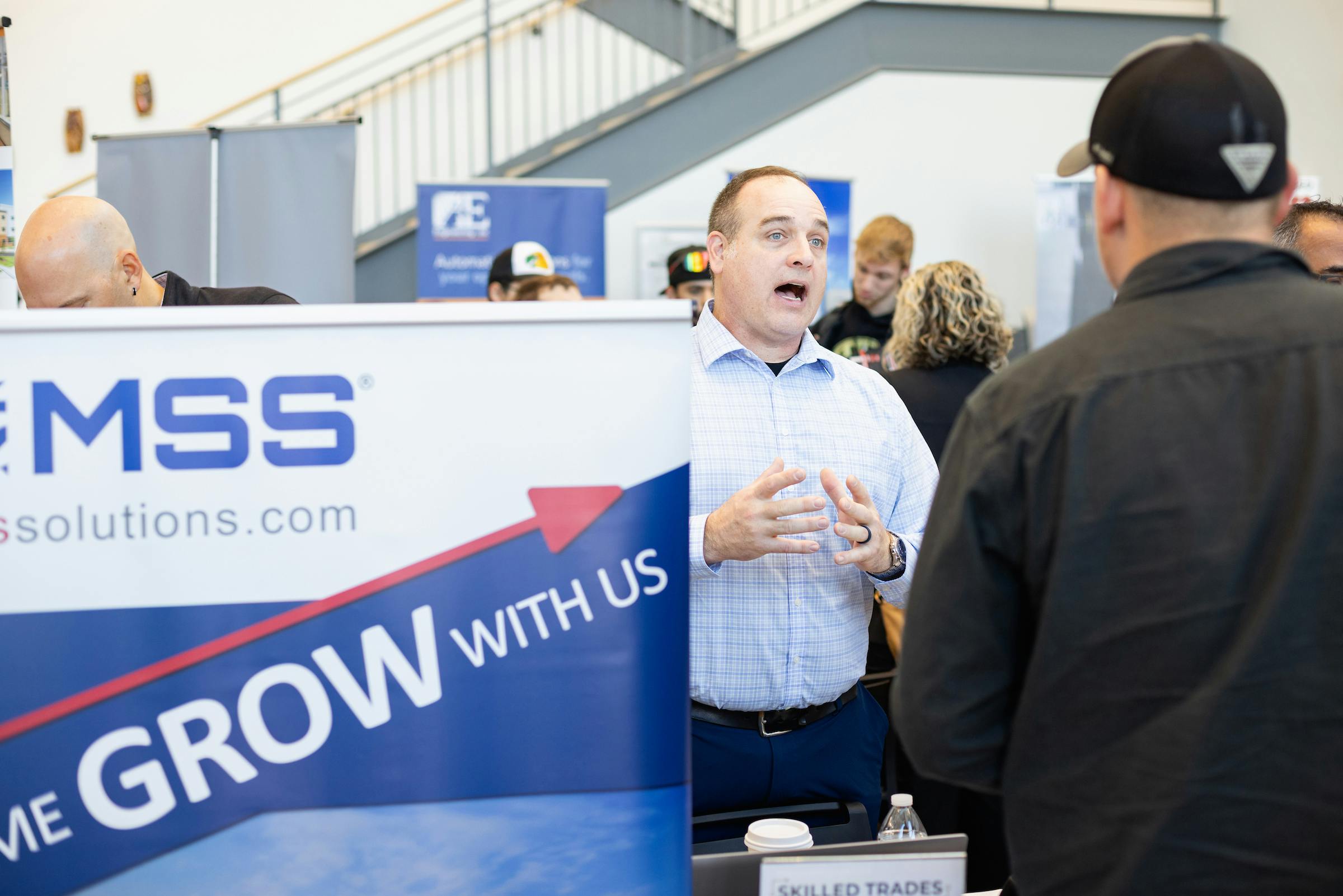 Job recruiter standing next to a marketing banner, speaking with a student