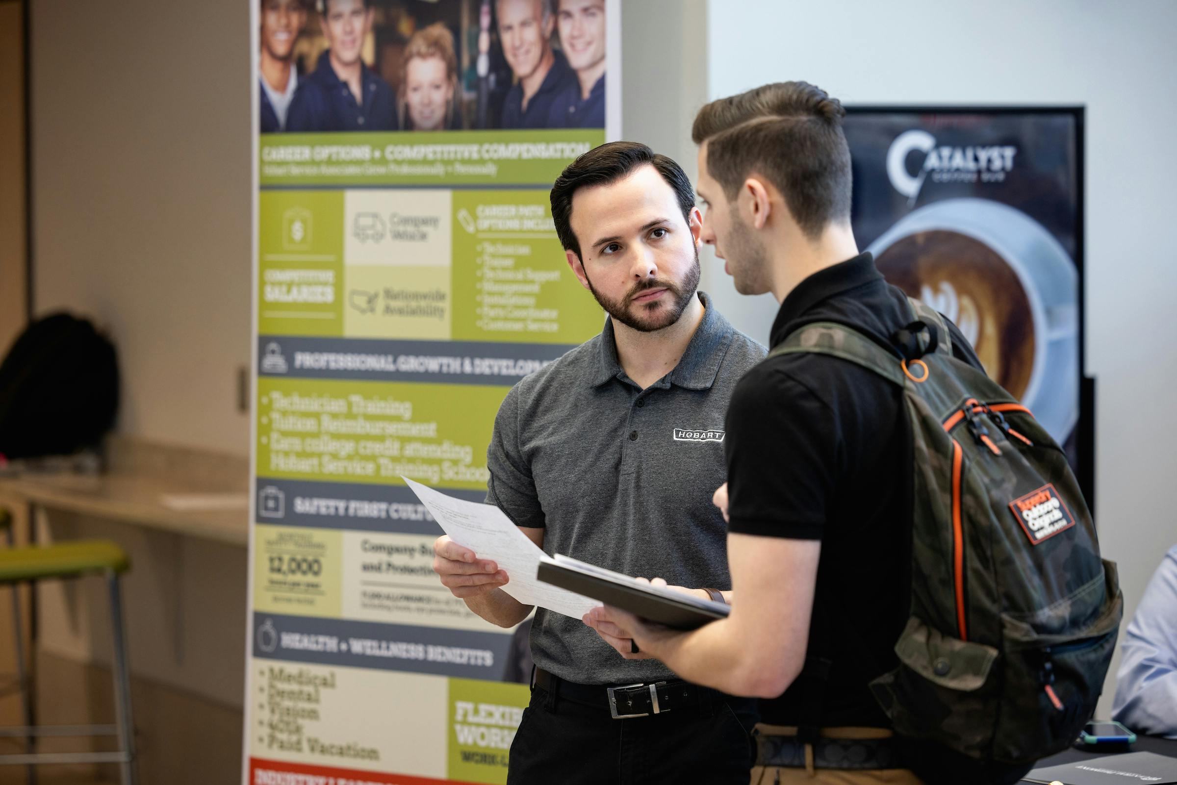 Interviewer speaking with student wearing a backpack