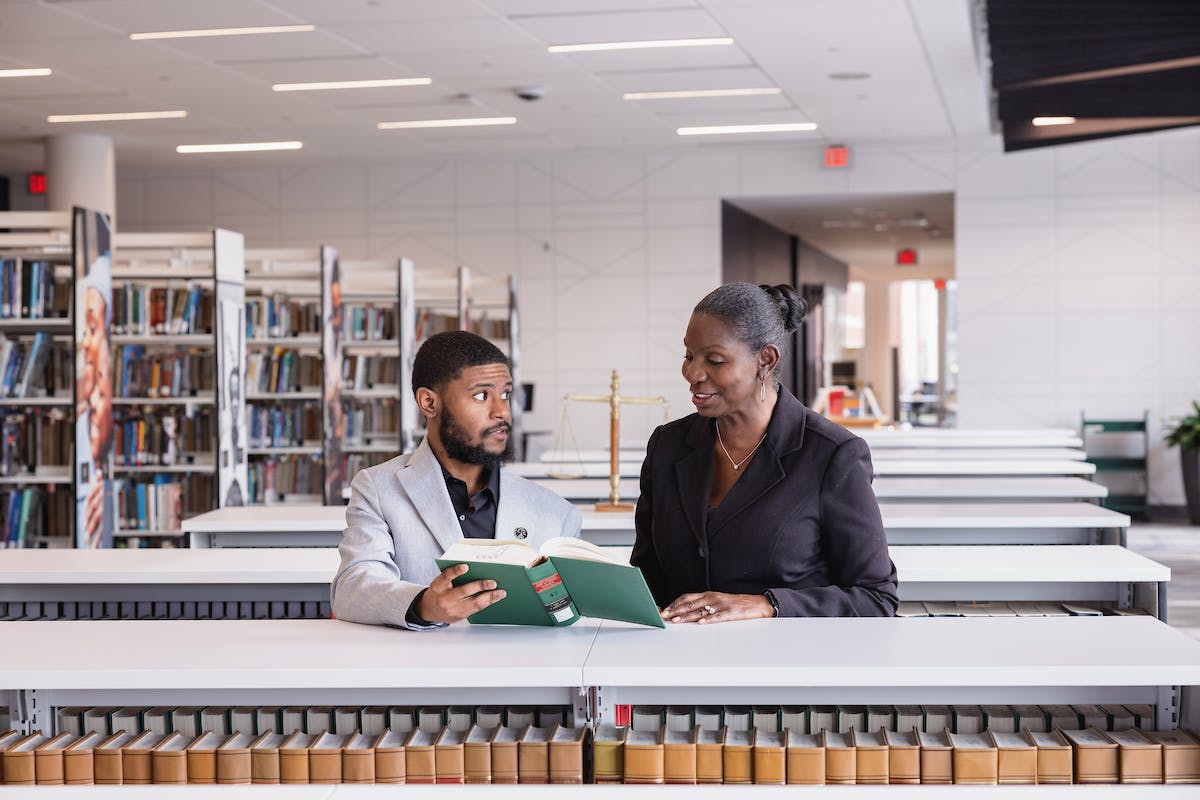 Paralegal student sharing a book in the library