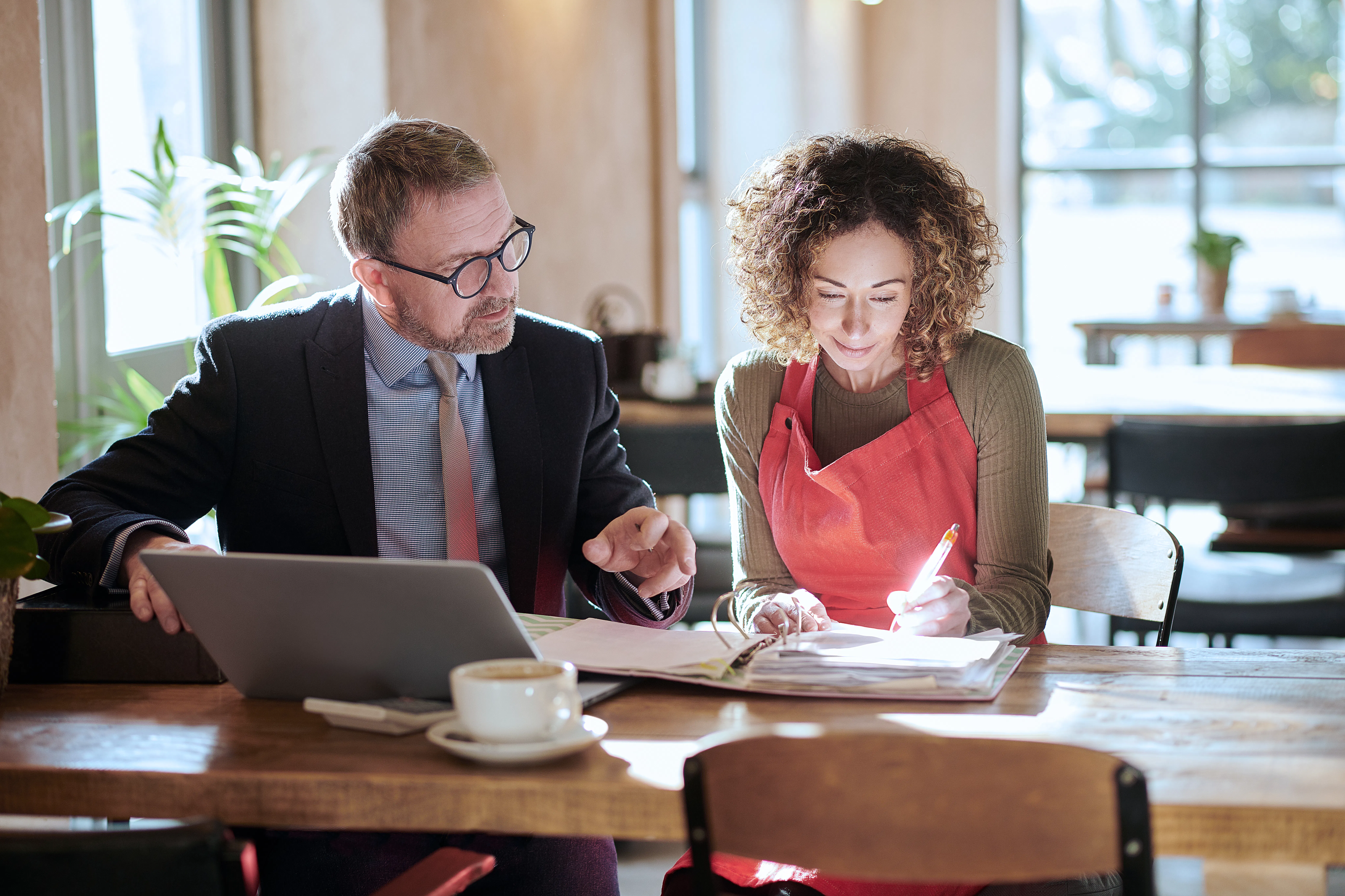 Business owner signs taxation forms as a tax professional looks on.