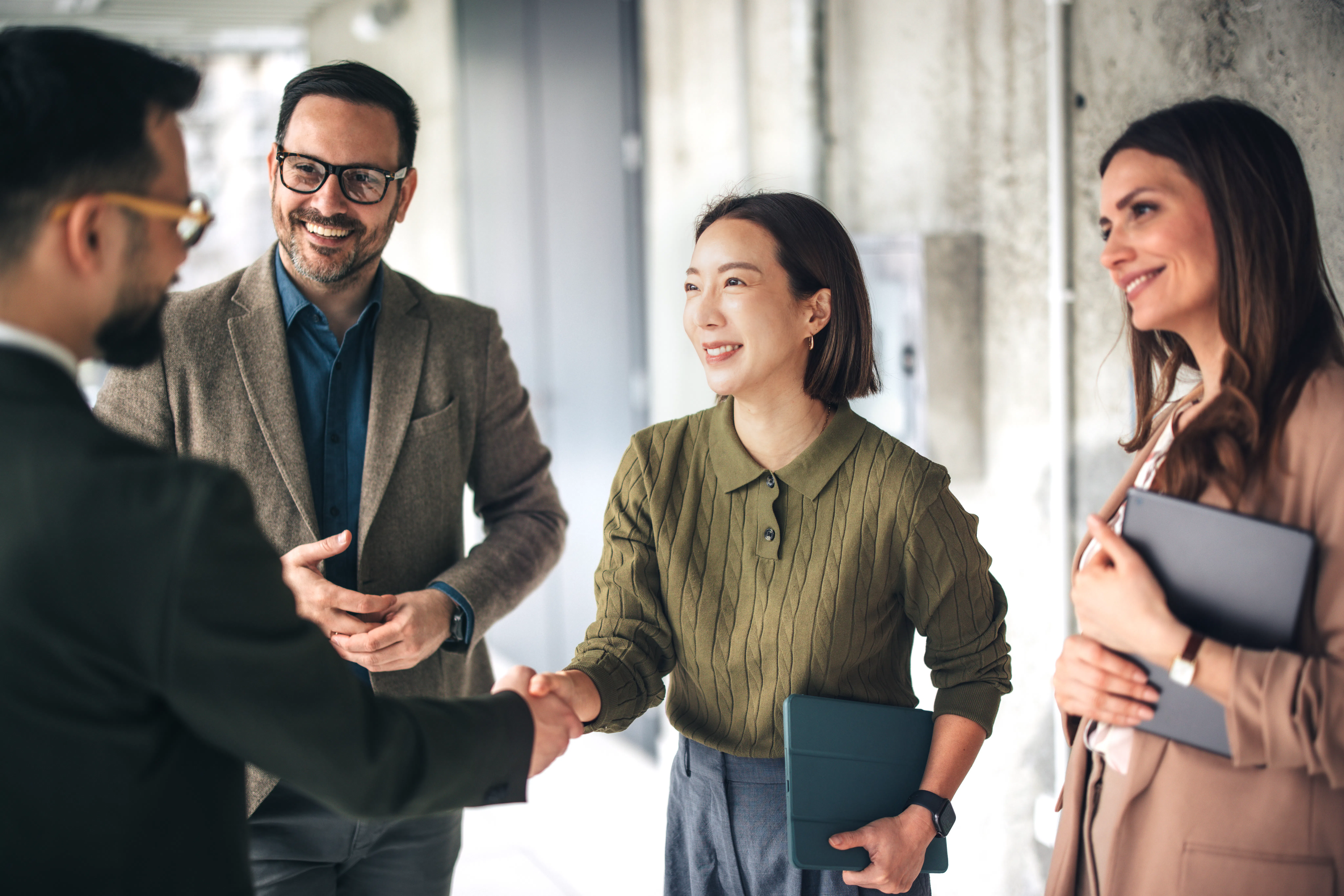 Tax professionals welcoming colleague with handshake.