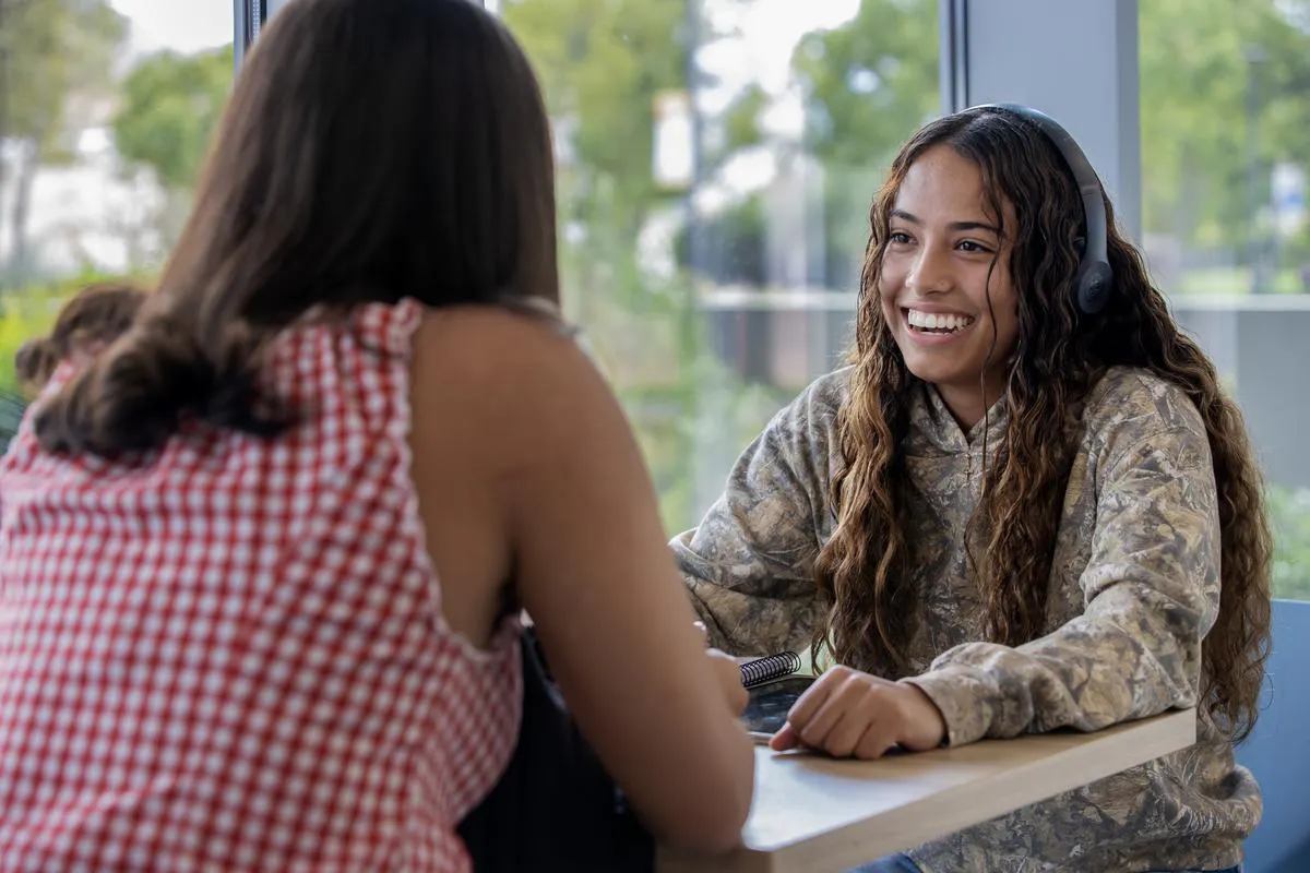 Two female students sitting at a table outside