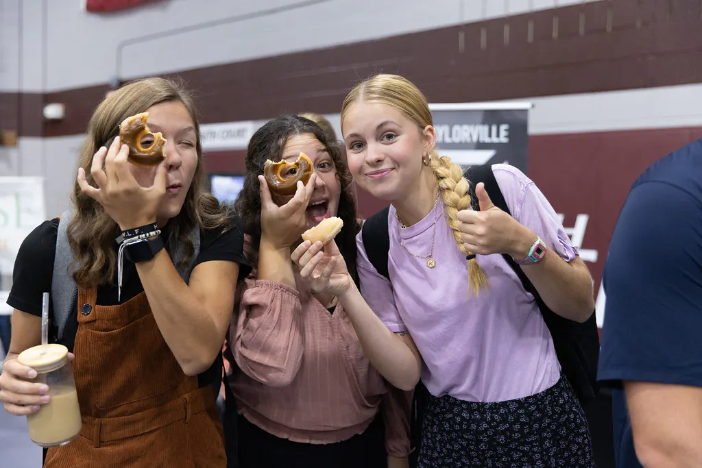 Faith students smiling with a donut