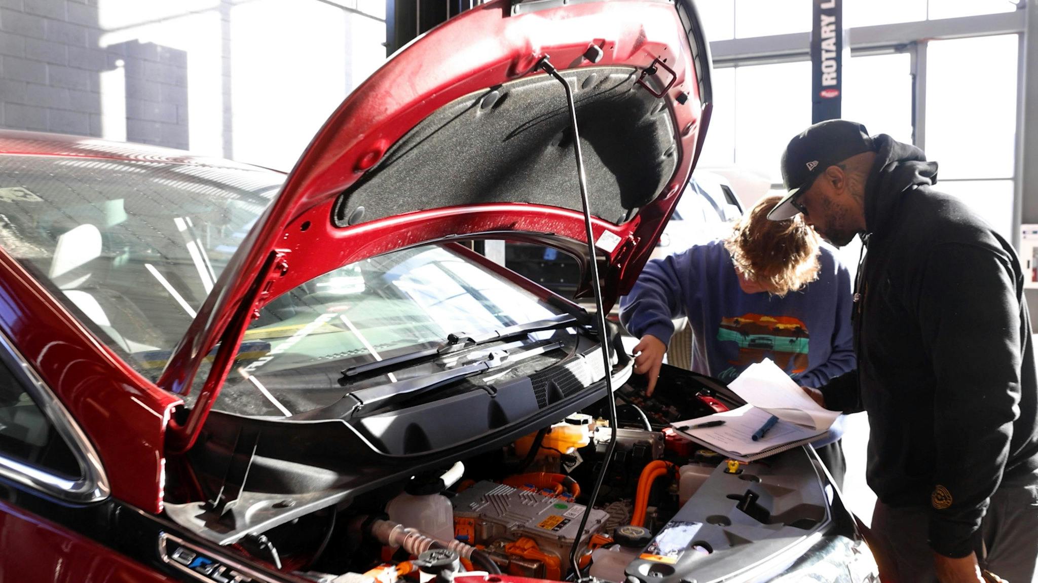Two students looking under the hood of a car in the electric vehicle class