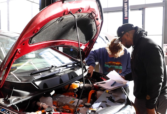 Two students looking under the hood of a car in the electric vehicle class