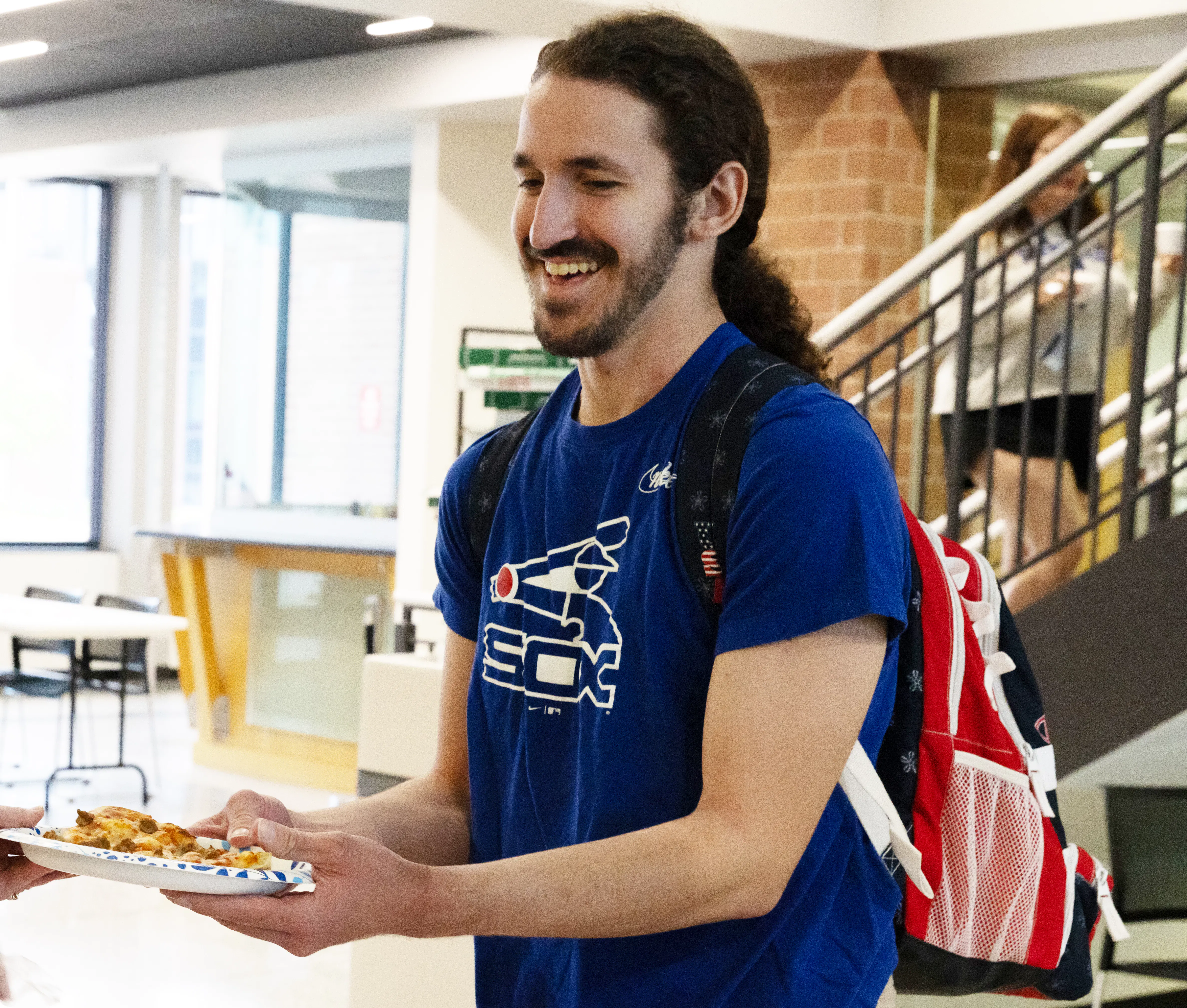 Image of Daniel Johnson smiling and receiving a piece of pizza at a Heartland event.