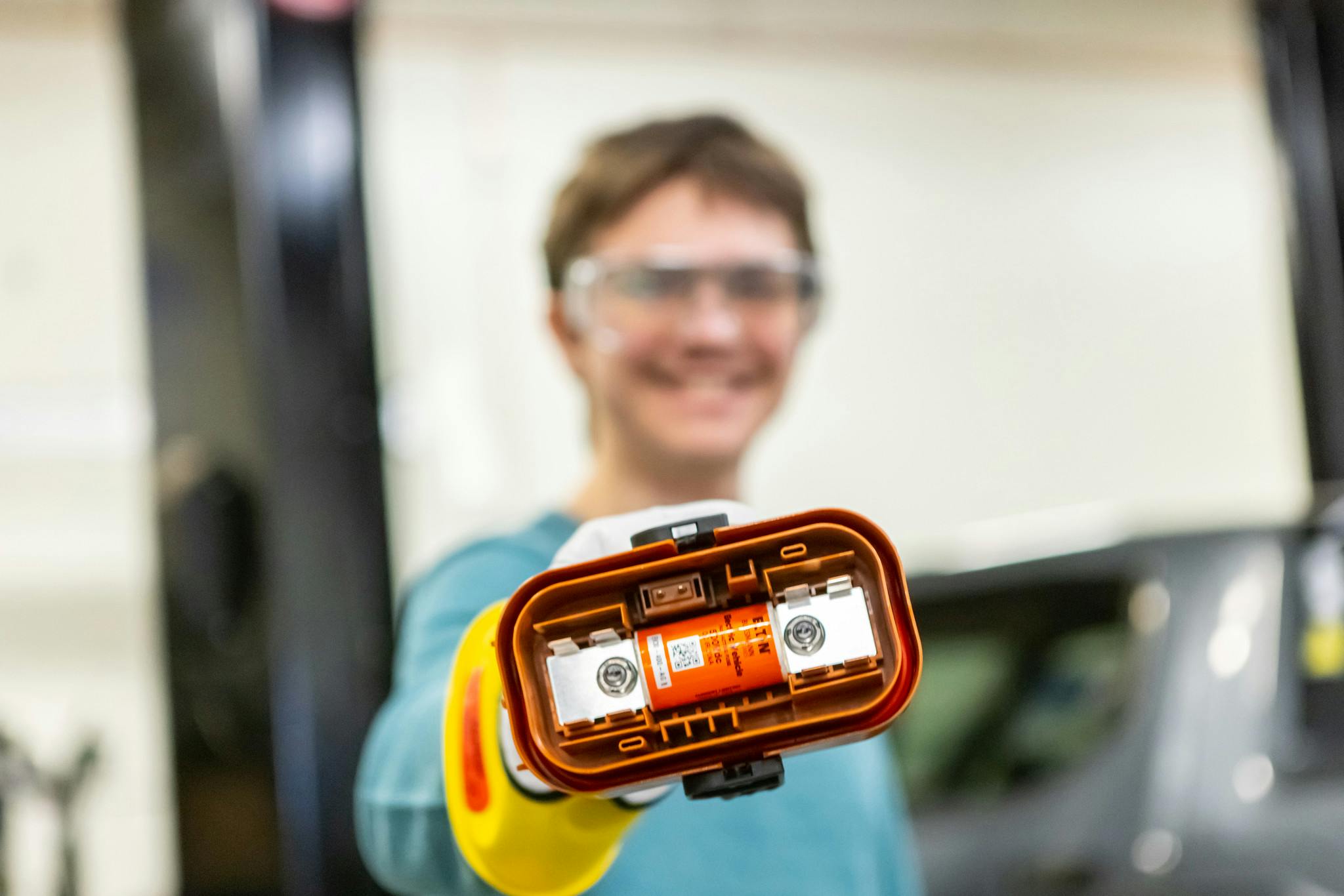Student holding up a tool for electric vehicle repair.