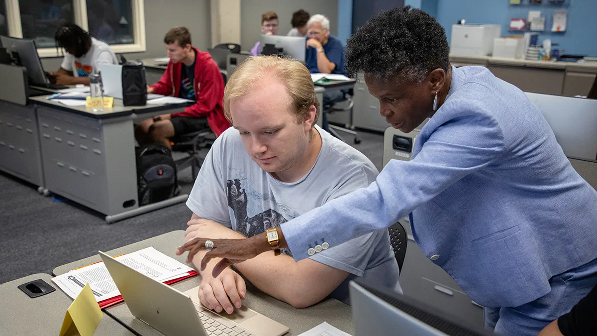 Accounting professor helps student in a tax preparation class.