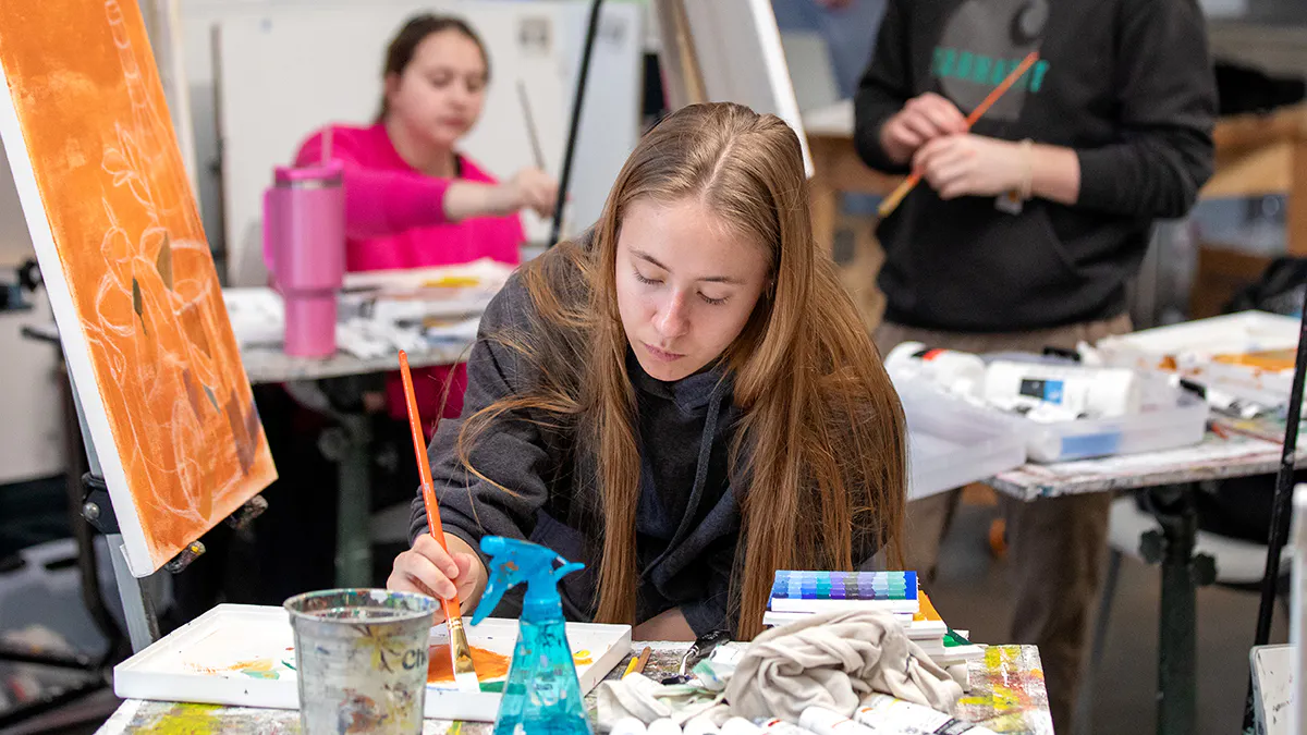 Painting student gathers paint on a brush.