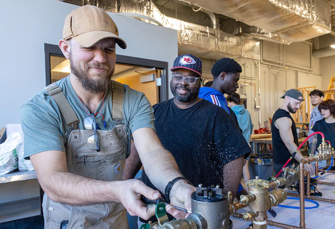 Students adjust valves to control water flow in plumbing lab.