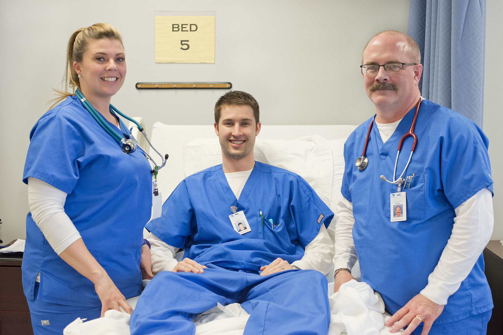Three nurses dressed in blue scrubs smiling 