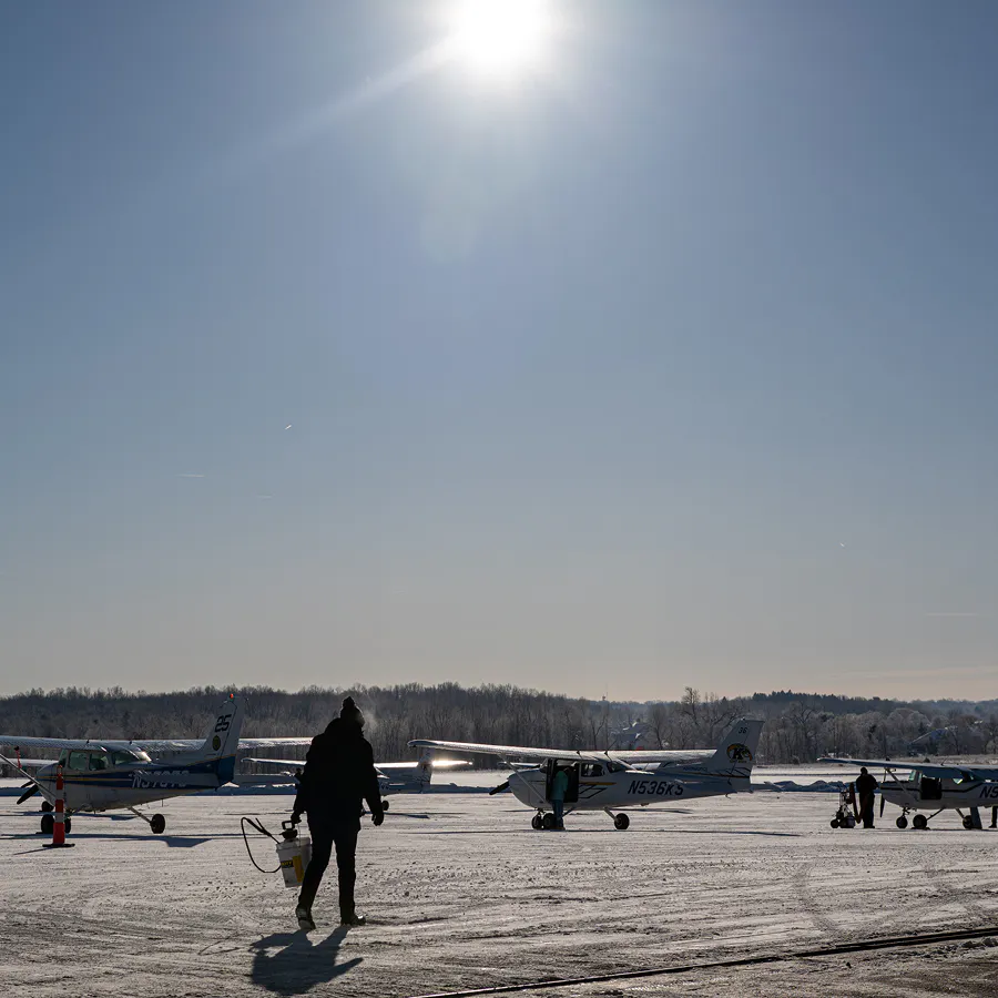 Person on tarmac at dusk with several kent state airplanes.