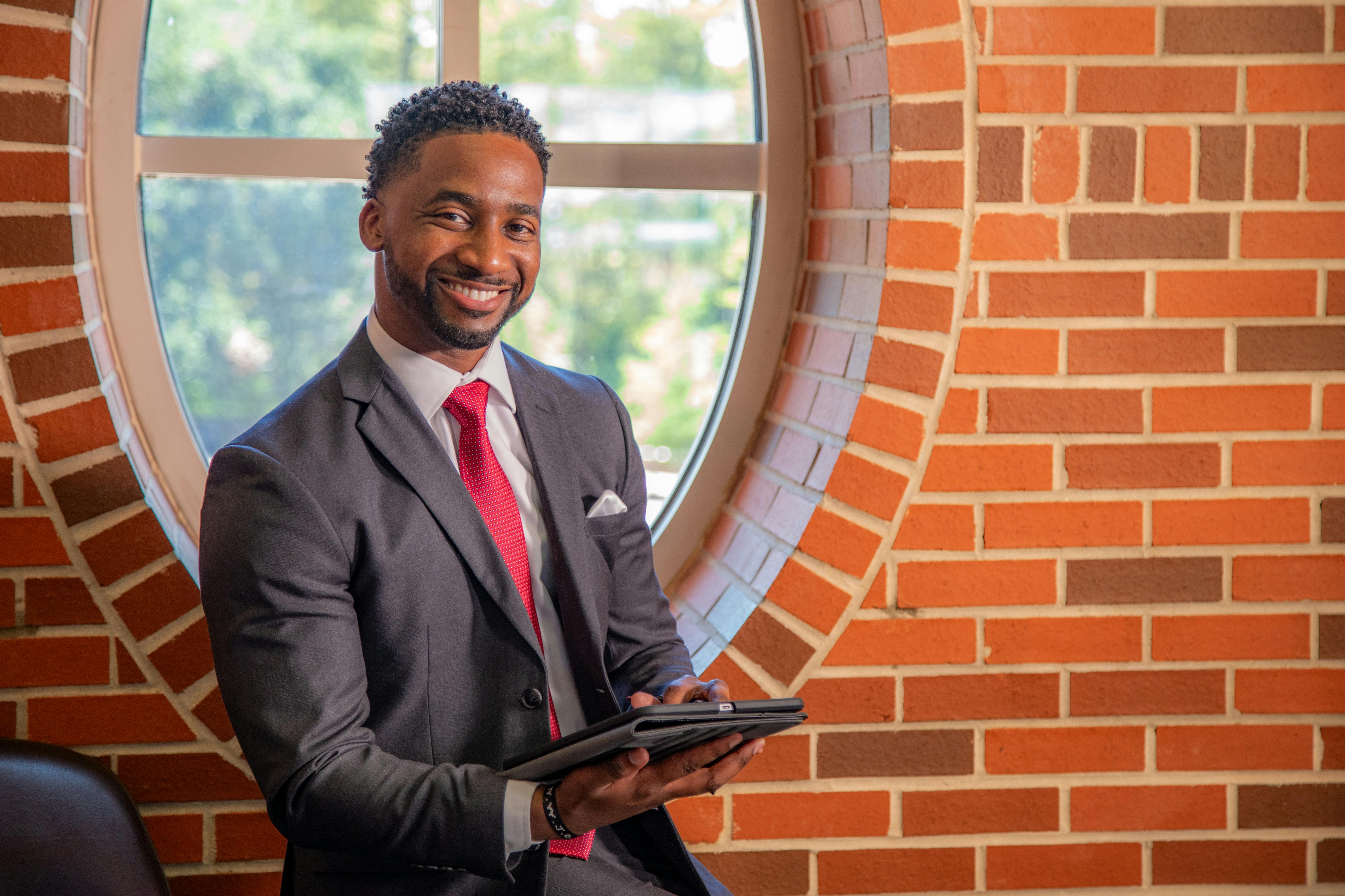 Ryan Owens, MBA alum, sits in front of a window holding a tablet. 