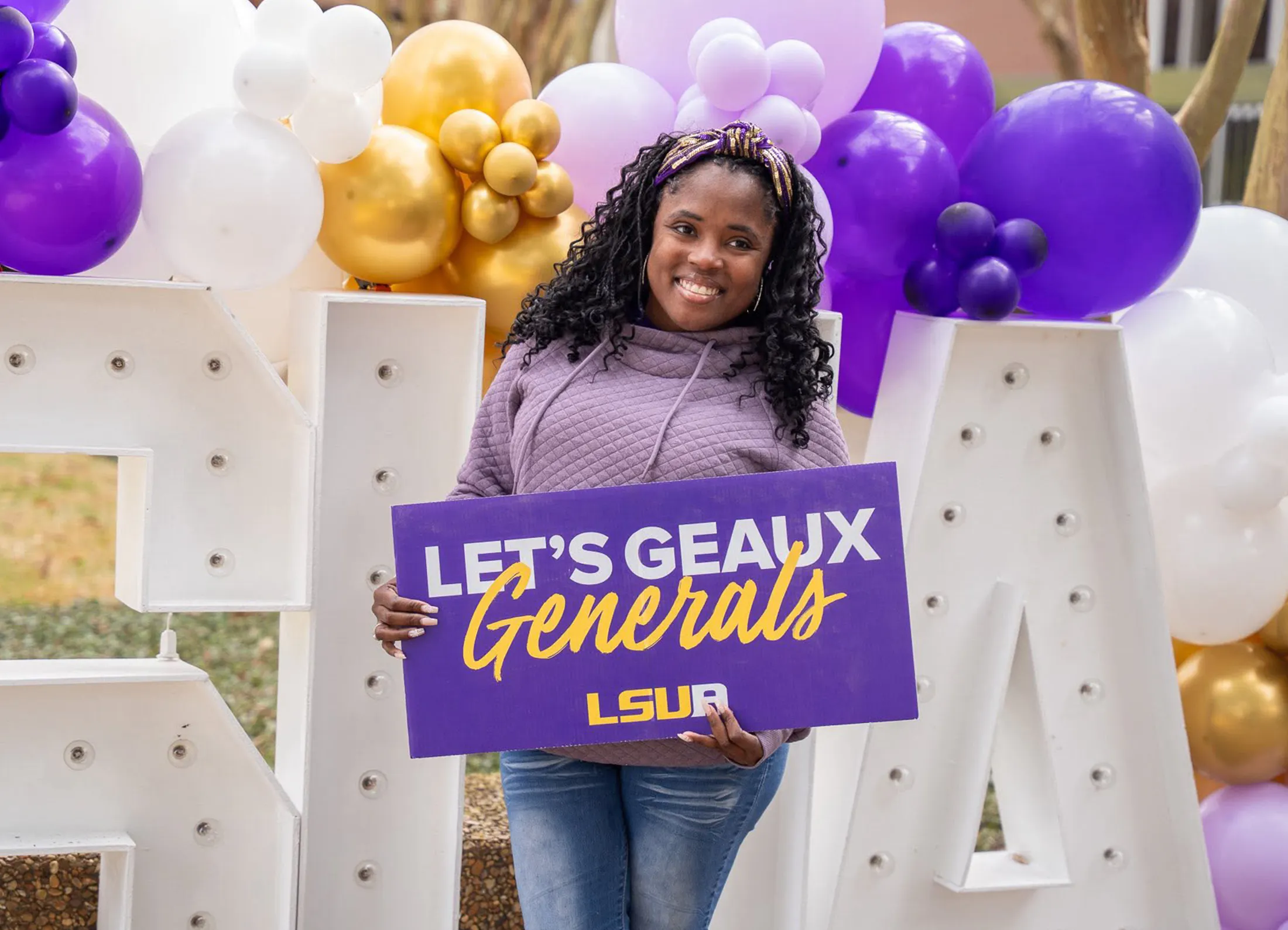 An LSUA Freshman posing with a "Let's Geaux Generals" sign.