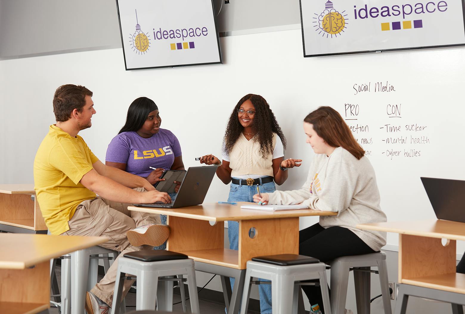 one male student with laptop, two female writing, and one presenting in the lsus ideaspace