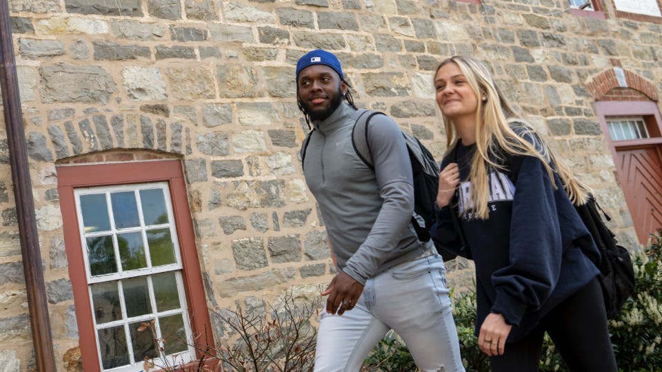 Two Moravian students walking on campus, one male, one female.