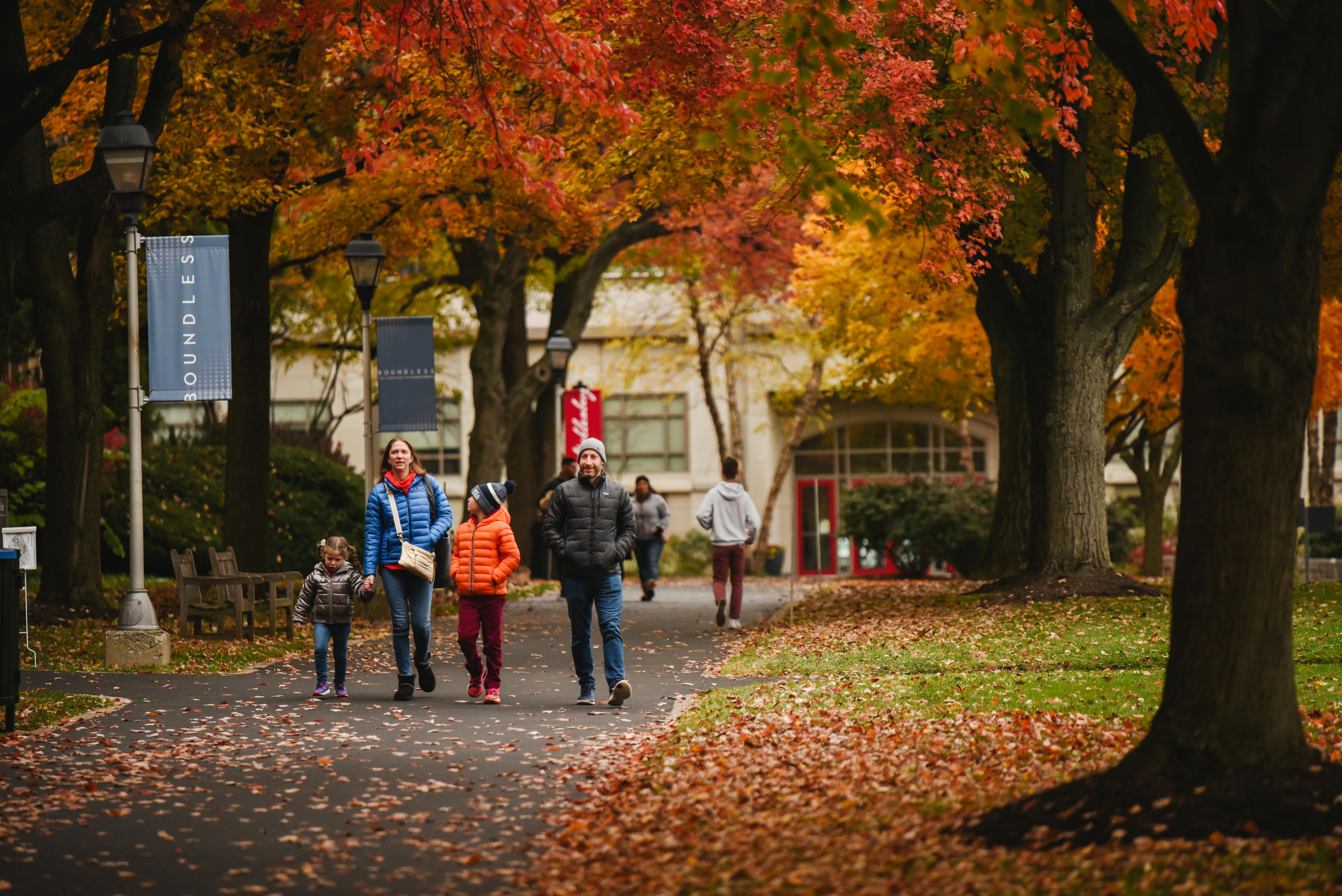 This is a picture of a group walking through campus during fall.
