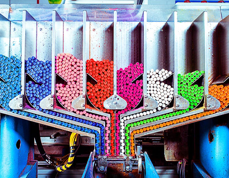 A variety of crayola crayon colors being funneled into packaging.