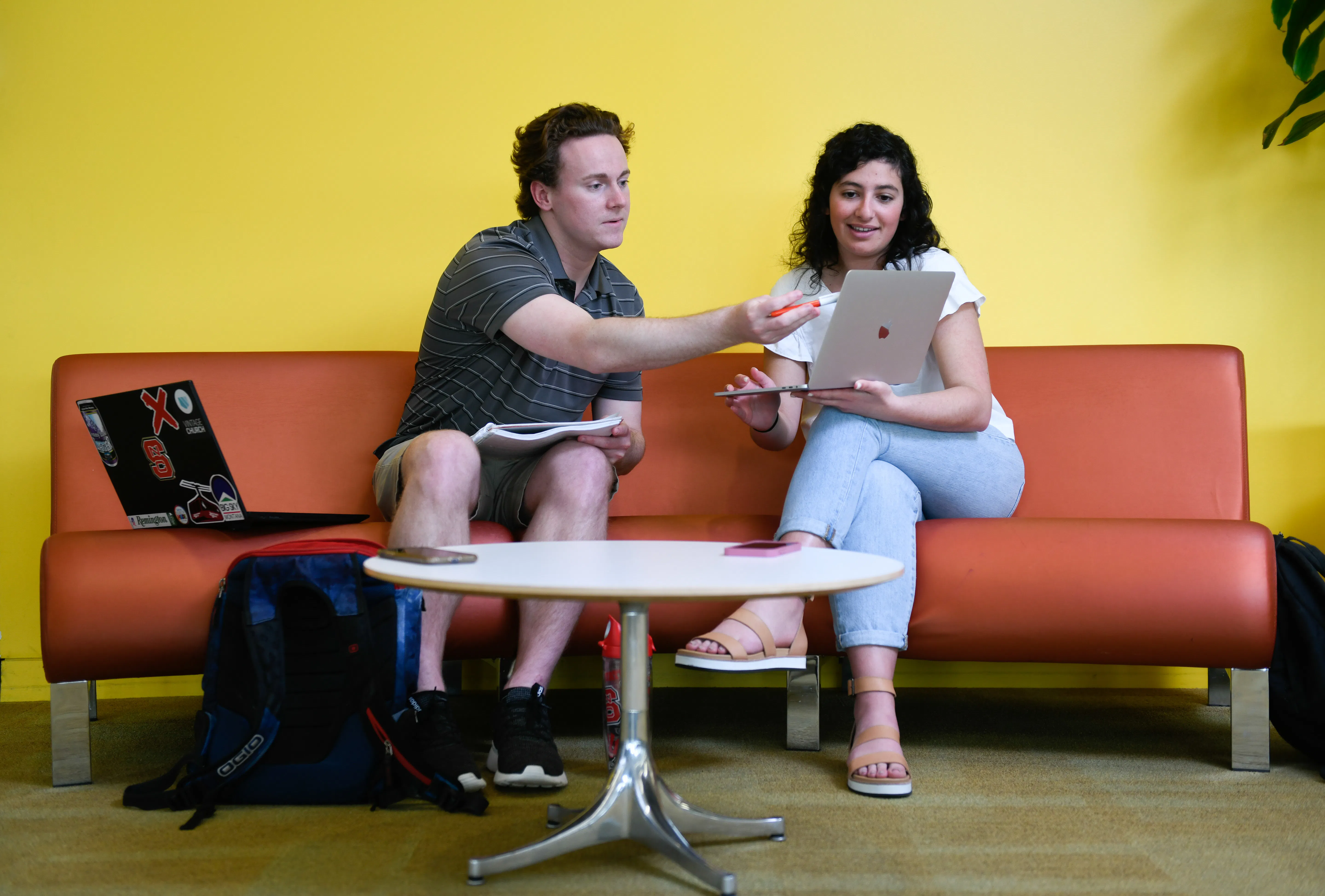 Students sitting and pointing at a lap top