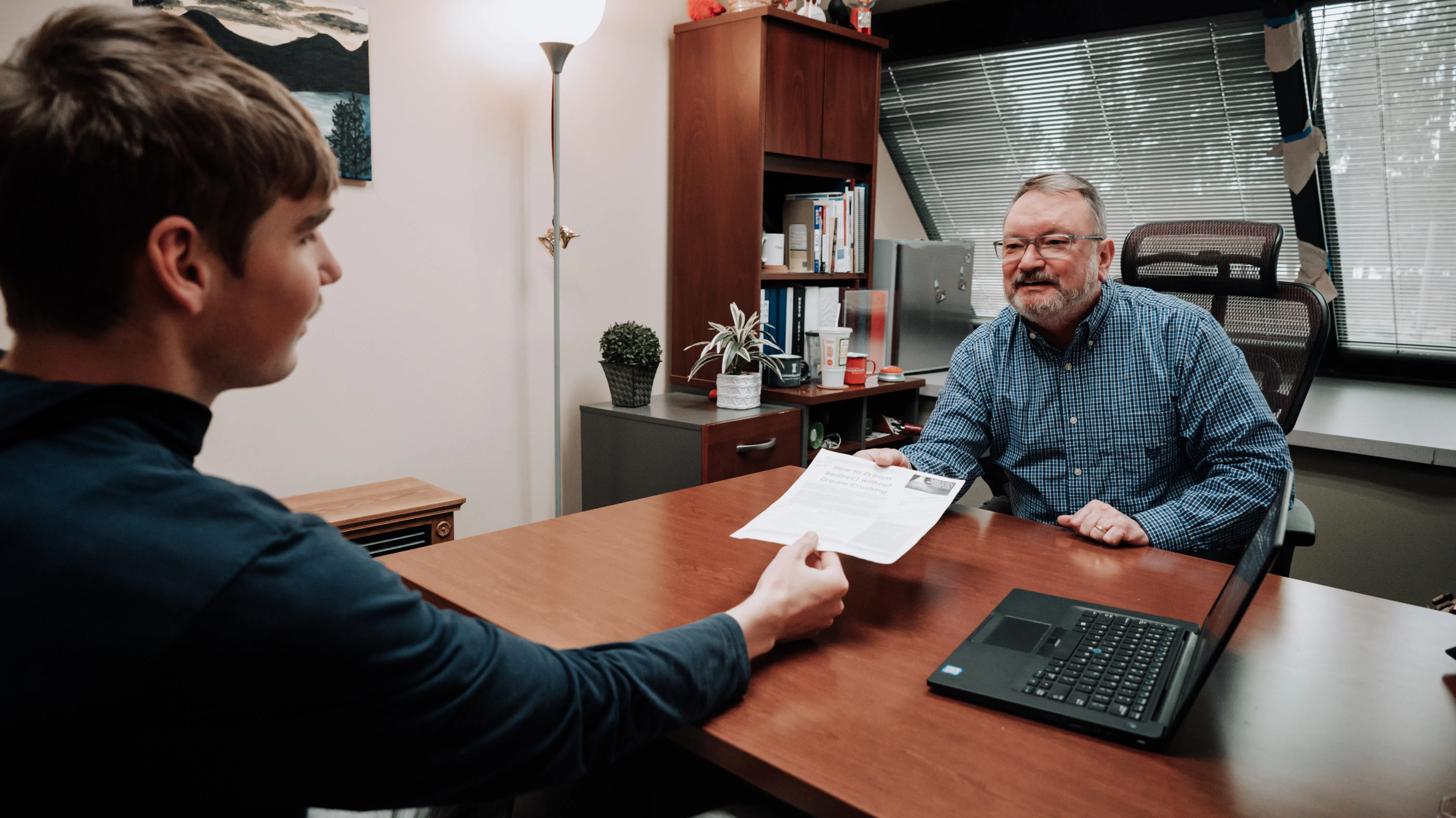 An advisor handing over a document to a student