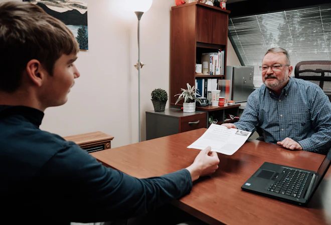 An advisor handing over a document to a student