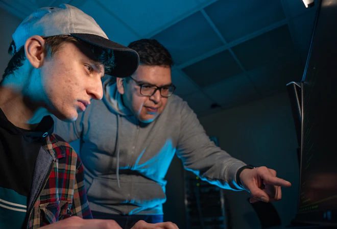A man guiding a student on a computer screen