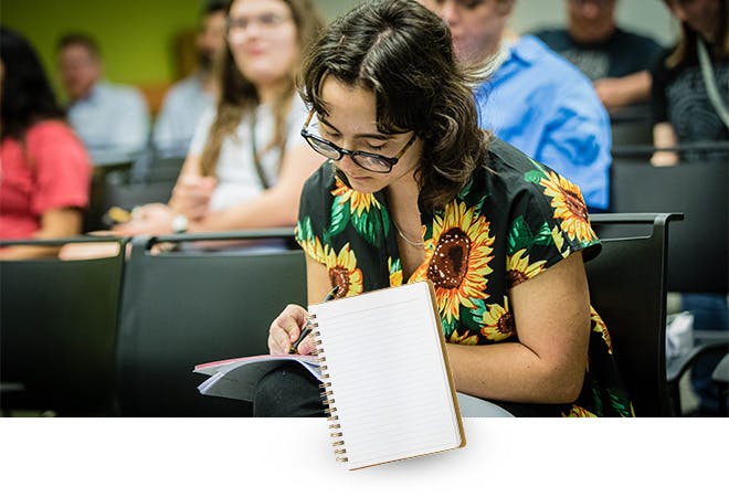 A student writes in a notebook for class.
