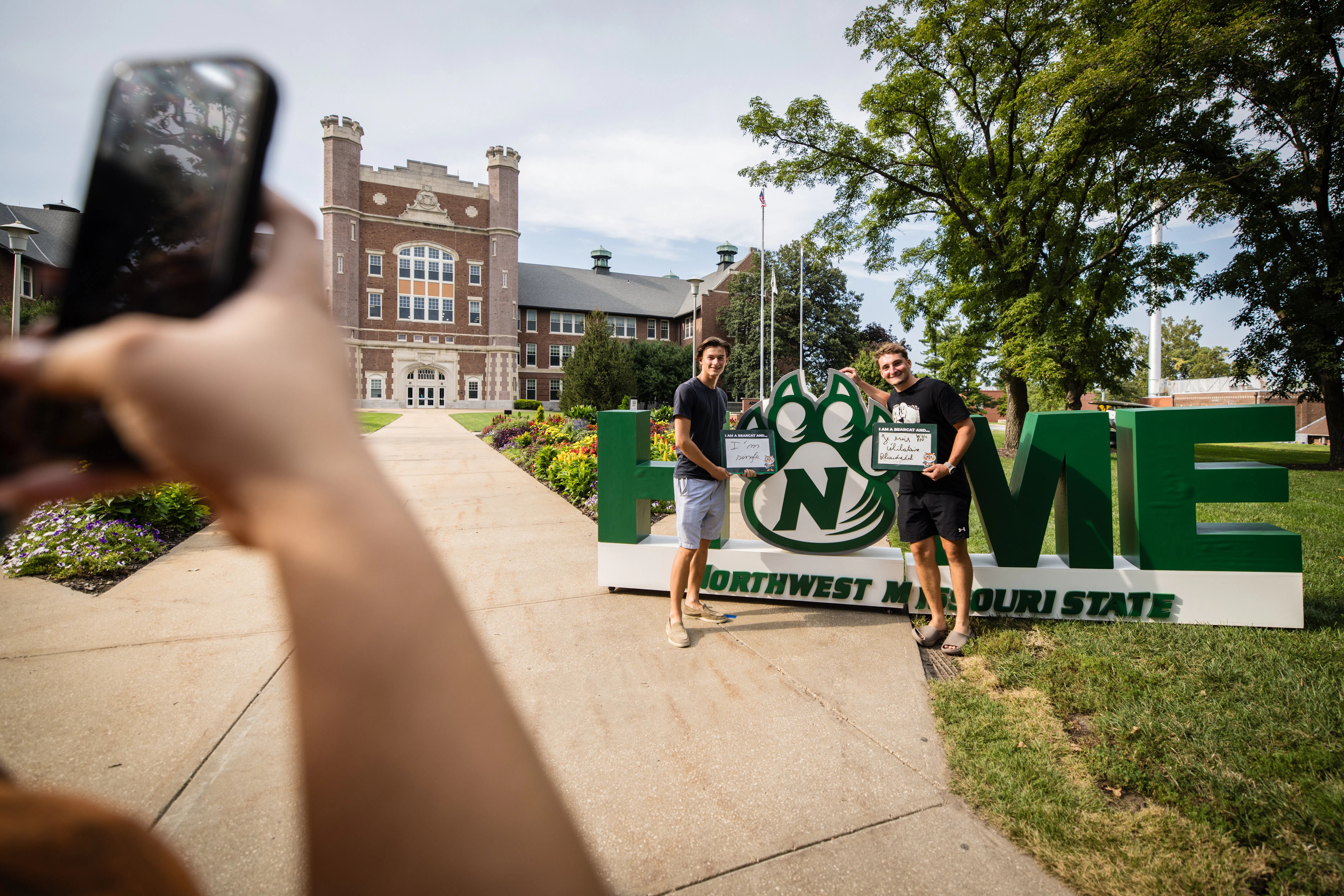 Two young men stand in front of the Home sign at Convocation.