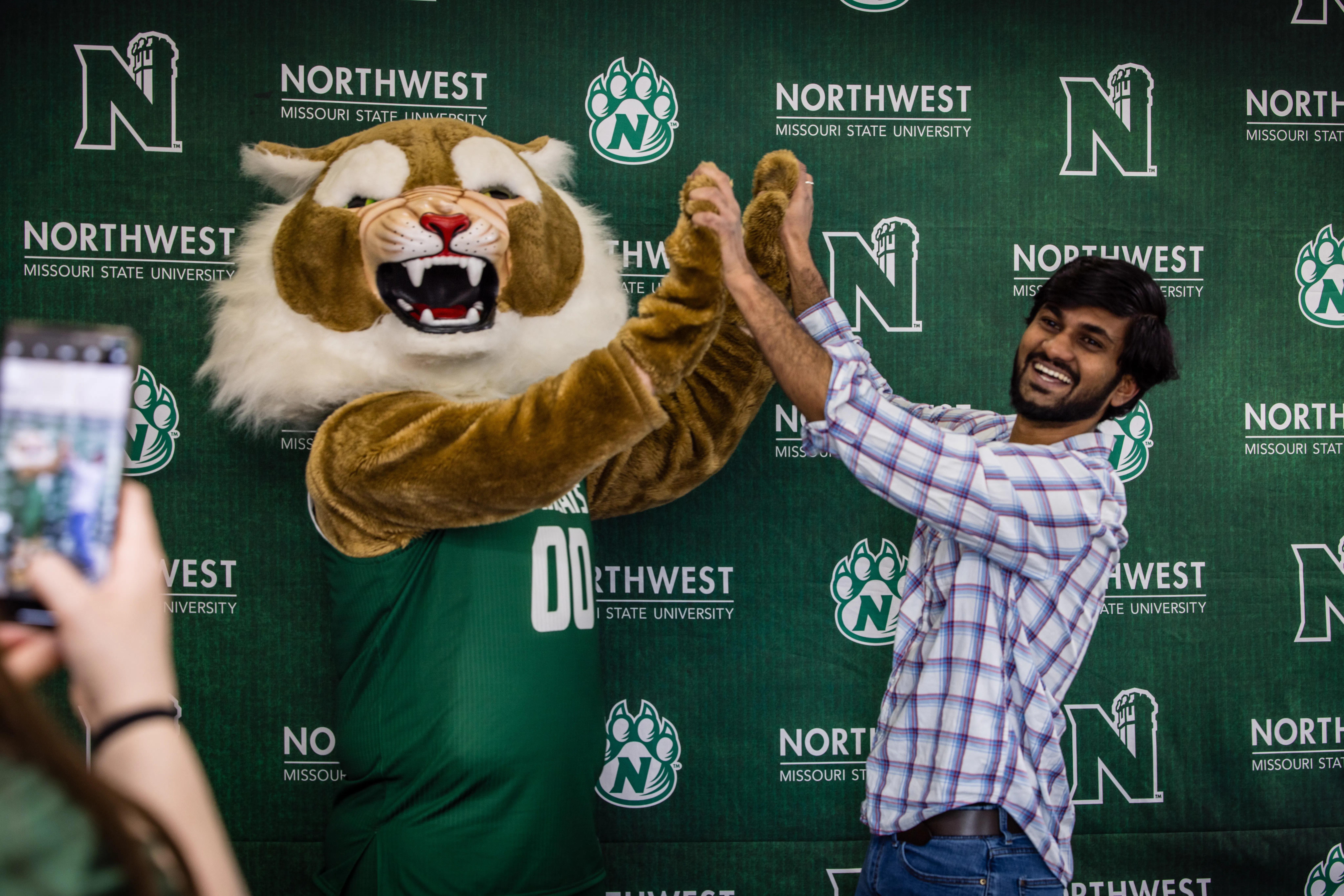 A student poses for a photo and high fives bobby bearcat