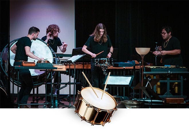 Students play percussion instruments during a performance.