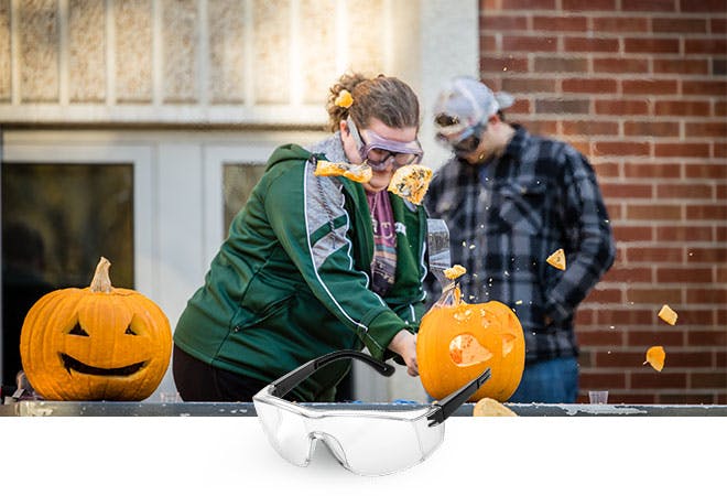 A student uses dry ice to carve a jack-o-lantern.