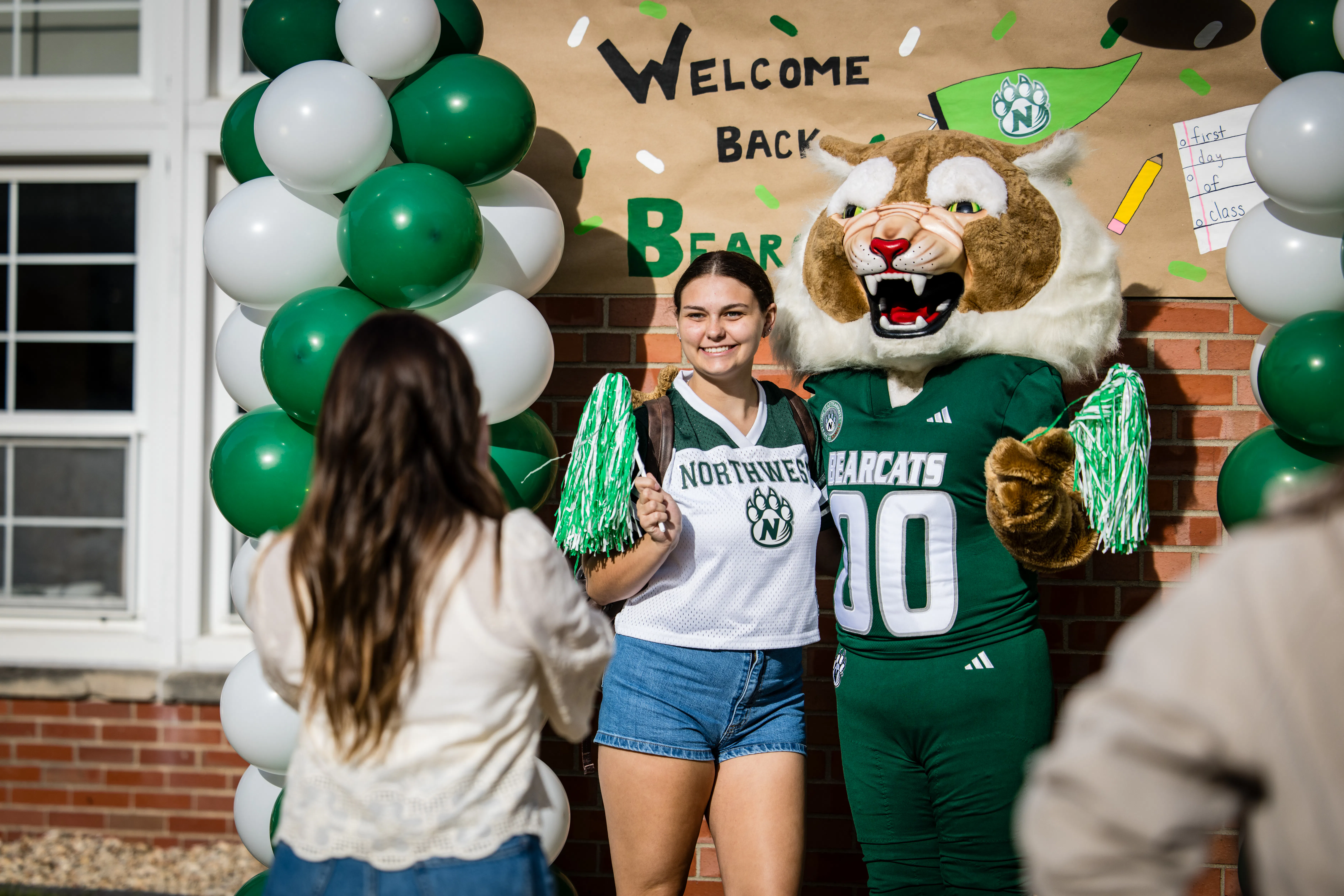 A student stands for a picture with Bobby Bearcat in a mascot costume.