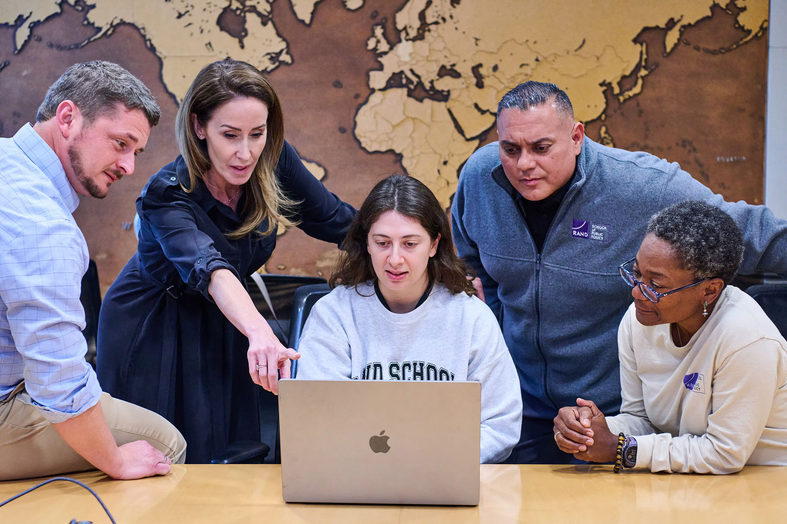 Students and a professor looking at analysis on a laptop