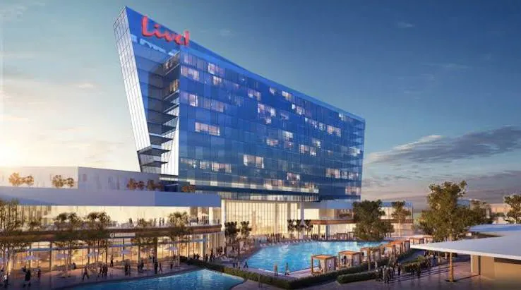 Rendering of the Live! hotel featuring a modern glass tower, outdoor pool, patio seating, and landscaped gathering spaces.