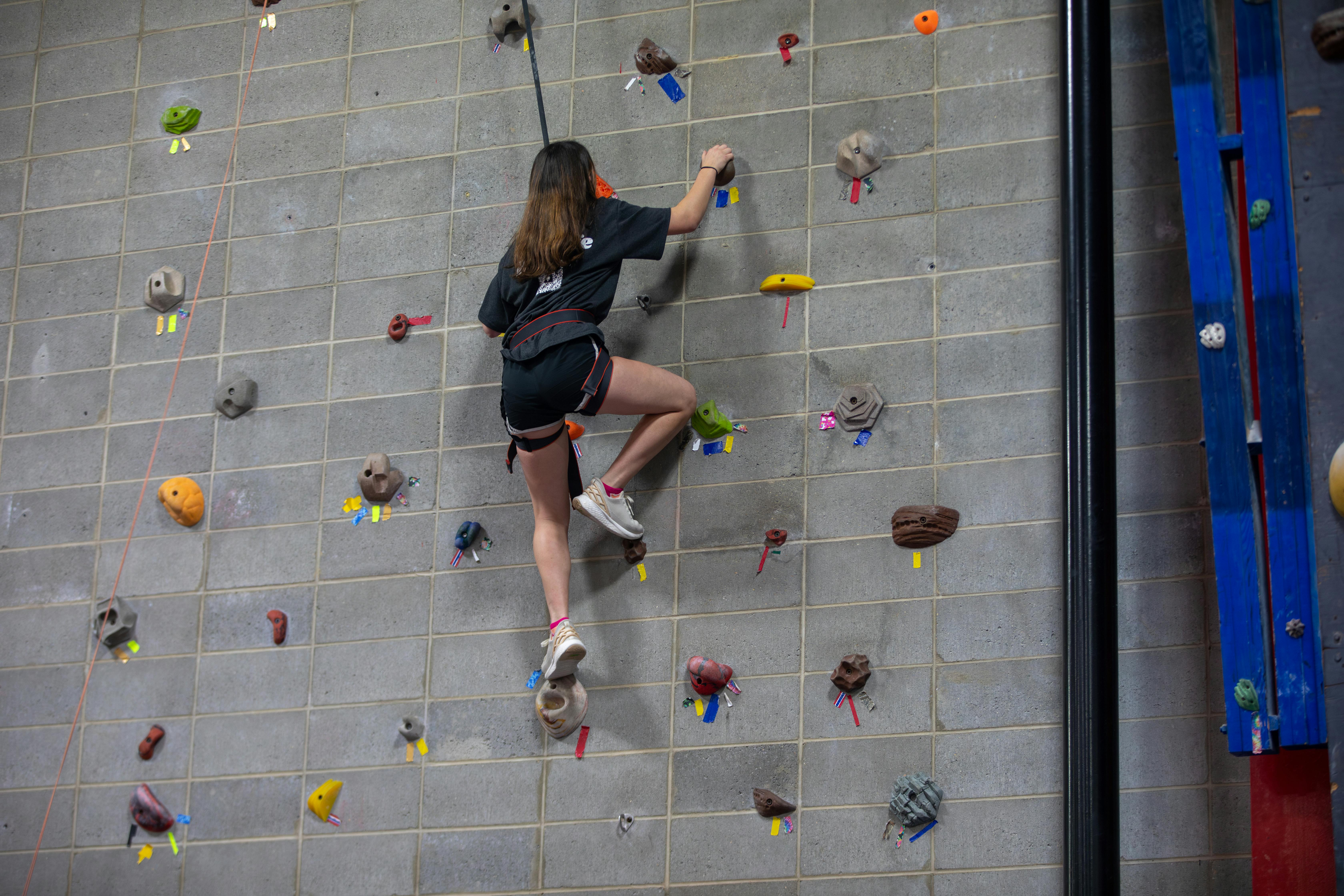 A student in the rock climbing club practices on the rock wall in the student recreation center. 